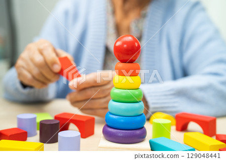 Asian elderly woman playing enhancing skill board game. Asian elderly woman playing enhancing skill board game. 129048441