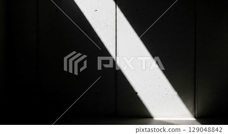 Abstract background with bright light beam on dark concrete wall, minimalist concept of hope or mystery with high contrast shadow play 129048842