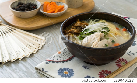 bowl of japanese chicken rice soup with pickles and a decorative fan nearby 129049128