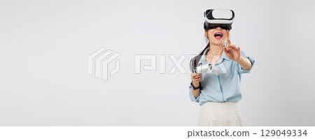 VR game focus as smiling Young woman point or touches VR game panel using stick controller, fully engaged in virtual reality experience. isolated studio white background 129049334