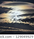 The morning sun peeks out from between the clouds in a fantastical way. 129049929