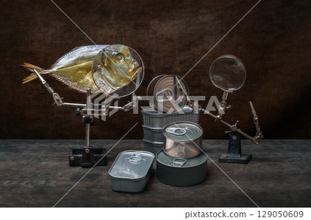 Still life with moonfish, canned food and a magnifying glass. Still life with moonfish, canned food and a magnifying glass. 129050609