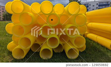 Bright yellow pipes stacked in outdoor area for construction needs, construction scene shows raw materials, construction visuals support infrastructure, urban planning, and industrial design content 129050692