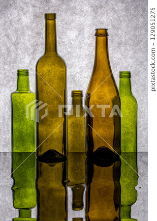 Still life with colored bottles on a reflective surface Still life with colored bottles on a reflective surface 129051275