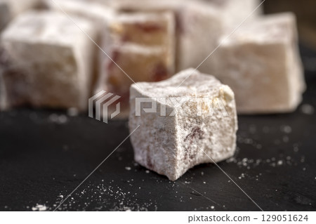 sweet lukum slices with cherry slices on a black board , cubes of sweet Turkish delight with the addition of dried red berries in powdered sugar sweet lukum slices with cherry slices on a black board , cubes of sweet Turkish delight with the addition of dried red berries in powdered sugar 129051624