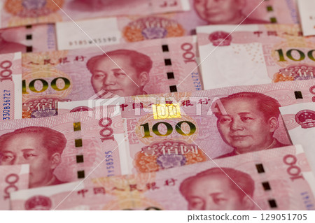 Chinese paper money of one hundred yuan in ultraviolet light, the obverse of a large number of genuine Chinese yuan money stacked on top of each other, which shines with an ultra violet Chinese paper money of one hundred yuan in ultraviolet light, the obverse of a large number of genuine Chinese yuan money stacked on top of each other, which shines with an ultra violet 129051705