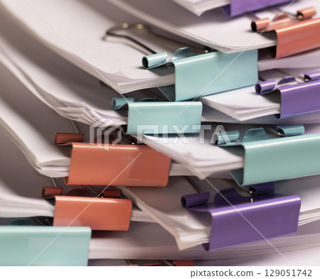 a large number of white blank sheets of paper are connected by multicolored metal clips 129051742