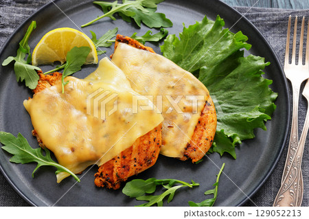 grilled chicken breast topped with melted cheese 129052213