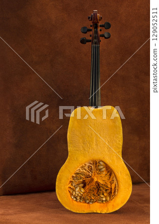 Still life with a cut pumpkin and fretboard on a brown background 129052511