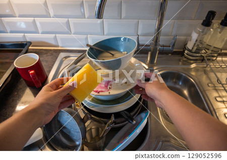 Female hands washing dishes in kitchen, clean space - clean mind 129052596