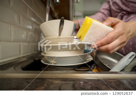 Female hands washing dishes in kitchen, clean space - clean mind 129052637