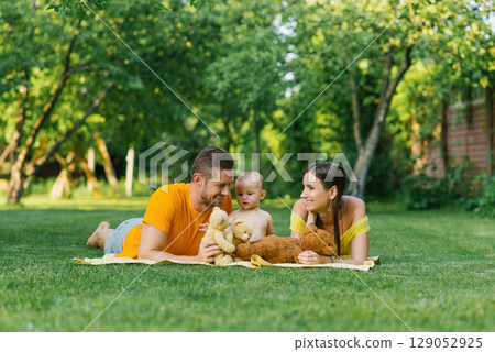Family Lying On Blanket Outdoors With Teddy Bears 129052925