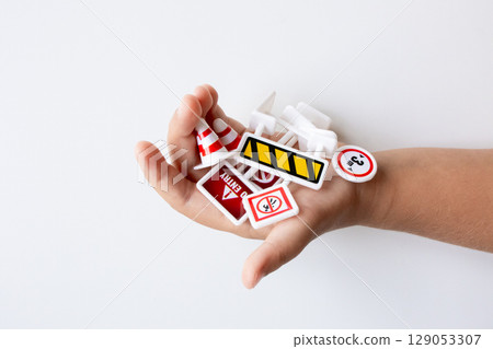 Child hand holding miniature traffic signs on white background Child hand holding miniature traffic signs on white background 129053307