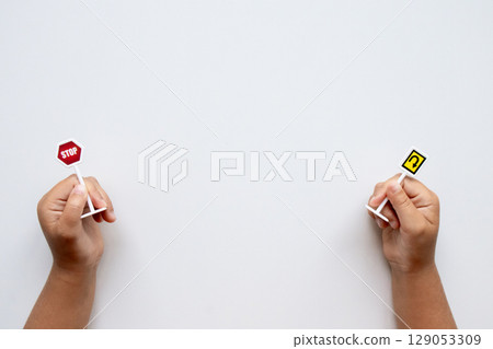 Child hands holding miniature stop and U turn signs against white background 129053309