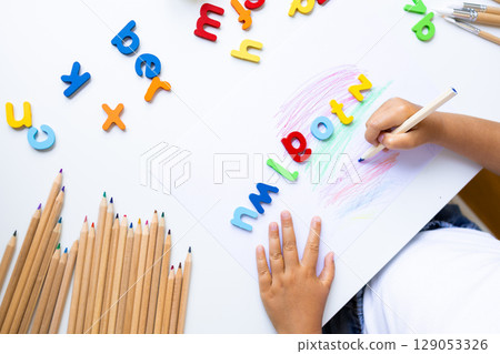 Child learning alphabet with colored pencils and foam letters on white table Child learning alphabet with colored pencils and foam letters on white table 129053326