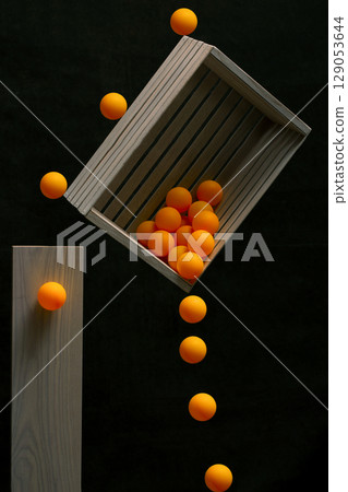 Still life with a wooden box and falling balls 129053644