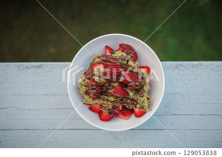 Homemade Dubai chocolate strawberry dessert with kataifi, pistachio paste, milk chocolate and fresh strawberries. Top view, vertical photo. Street food desserts and sweets. Copy space for text. 129053838