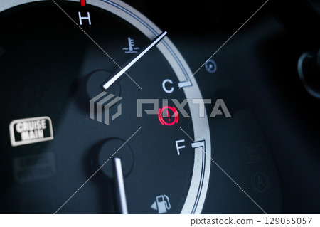 Red brake system warning light on car dashboard next to fuel and temperature gauge indicators. 129055057