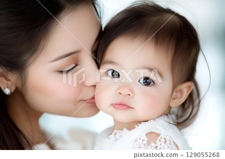 Tender close-up image of a woman with elegant earrings holding a baby. Tender close-up image of a woman with elegant earrings holding a baby. 129055268