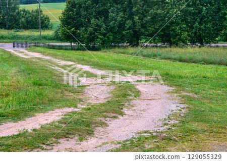 Quiet country path winding through lush green fields under a clear sky Quiet country path winding through lush green fields under a clear sky 129055329