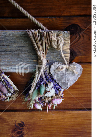 Dried floral arrangement with heart accent hanging on wooden wall 129055384