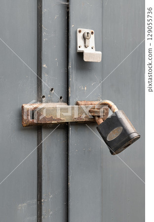 Iron locked padlock in Rusty metal door lock hasp latch on the Wooden door frame. 129055736