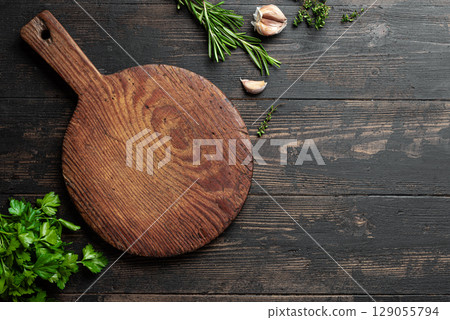 Empty wooden round platter with herbs and garlic 129055794