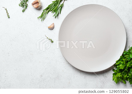 Empty white ceramic plate with herbs and garlic 129055802