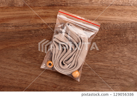 Plastic transparent pack with new brown shoe laces on wooden table 129056386