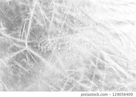 Worn scratched silver foil material with folds and wrinkles. Abstract light gray background Worn scratched silver foil material with folds and wrinkles. Abstract light gray background 129056409