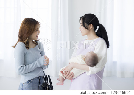 A mother going out with a babysitter holding a baby A mother going out with a babysitter holding a baby 129056605