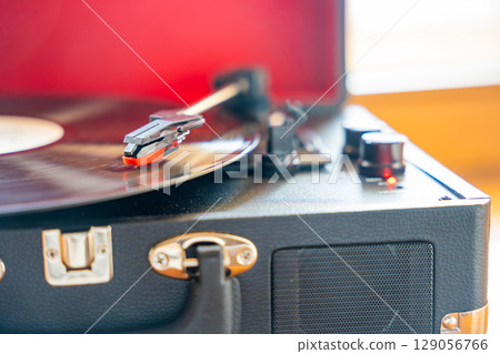 Close-up of record player needle tracking vinyl grooves during playback. Analog sound detail capturing retro music atmosphere. 129056766