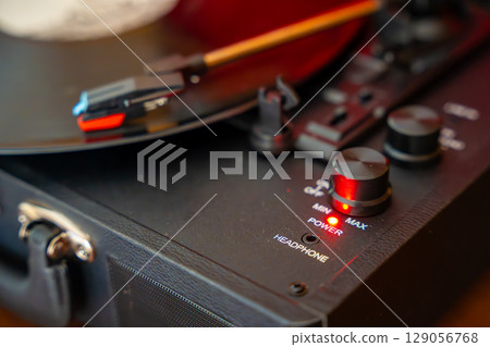 Close-up of record player needle tracking vinyl grooves during playback. Analog sound detail capturing retro music atmosphere. 129056768