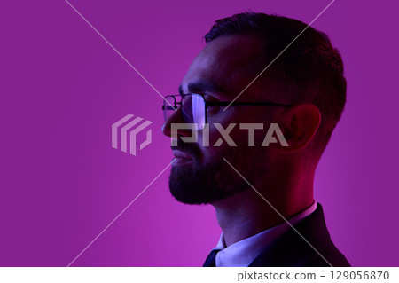Profile of a bearded man in glasses against a purple backdrop Profile of a bearded man in glasses against a purple backdrop 129056870