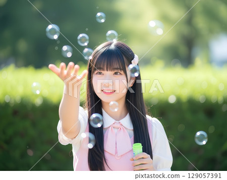 High school girls playing with soap bubbles in the park 129057391