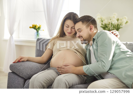 Caring husband touching belly of pregnant wife, expressing love and care to unborn baby Caring husband touching belly of pregnant wife, expressing love and care to unborn baby 129057996