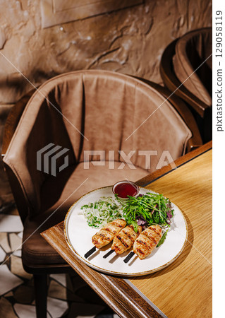 Delicious grilled skewers served with fresh salad at a cozy restaurant 129058119