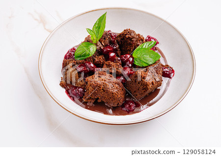 Delicious chocolate cake with cherry sauce and mint garnish served elegantly Delicious chocolate cake with cherry sauce and mint garnish served elegantly 129058124