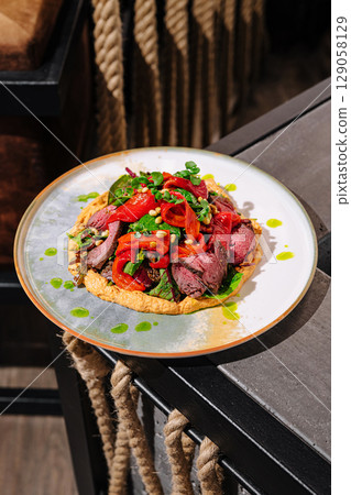 Delicious plate of grilled meat and vegetables served in a lively restaurant 129058129