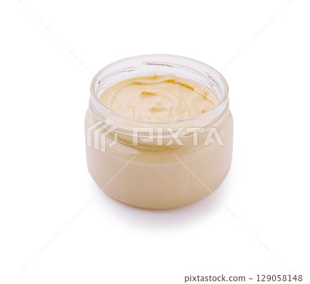 Creamy natural spread in a glass jar on a white background 129058148