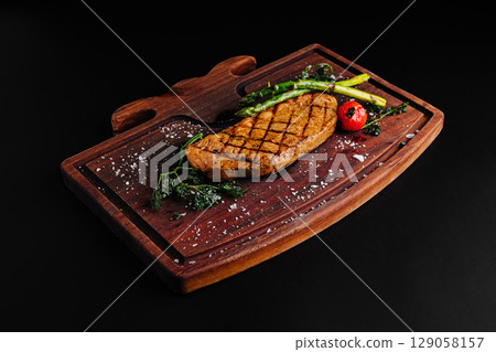 Juicy grilled steak served with asparagus and cherry tomatoes on wooden board Juicy grilled steak served with asparagus and cherry tomatoes on wooden board 129058157