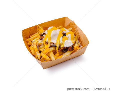 Loaded fries with cheese and toppings served in a paper tray 129058194