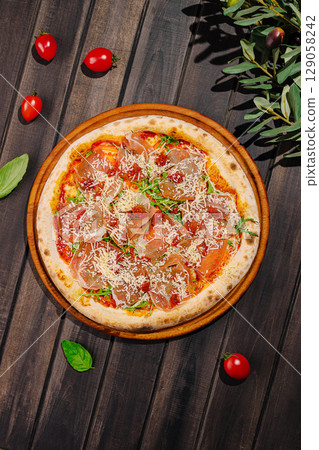 Delicious pizza topped with prosciutto and fresh ingredients on wooden table 129058242