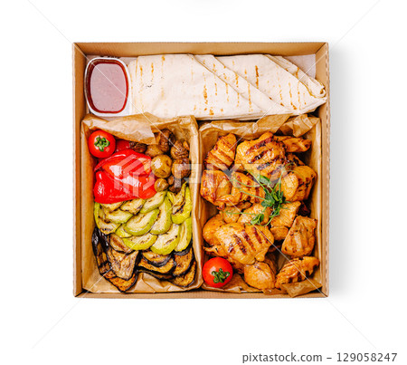Grilled chicken and vegetables with sauce in a takeout box for a tasty meal Grilled chicken and vegetables with sauce in a takeout box for a tasty meal 129058247