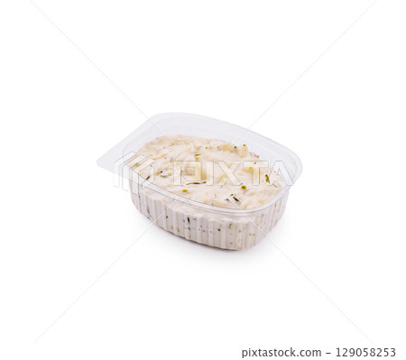 Creamy dip served in a plastic container with herbs visible on top 129058253