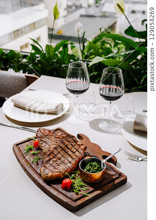 Steak dinner with red wine and fresh herbs in outdoor garden setting 129058269