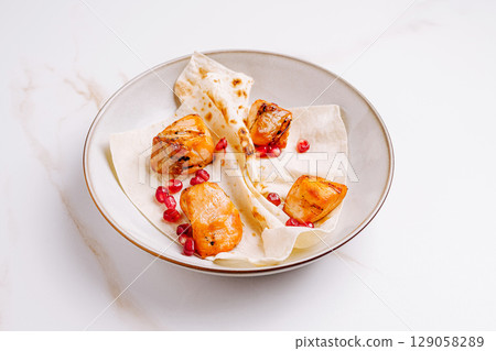Grilled sweet potatoes with pomegranate seeds on flatbread served in a bowl Grilled sweet potatoes with pomegranate seeds on flatbread served in a bowl 129058289