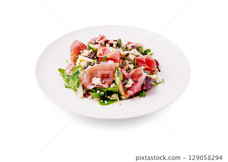 Vibrant salad with prosciutto, arugula, and mixed greens on a white plate Vibrant salad with prosciutto, arugula, and mixed greens on a white plate 129058294
