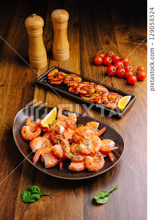 Succulent shrimp platter with grilled seafood and fresh tomatoes on wooden table 129058324