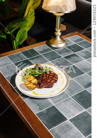 Delicious grilled steak with sides served on a stylish table Delicious grilled steak with sides served on a stylish table 129058325